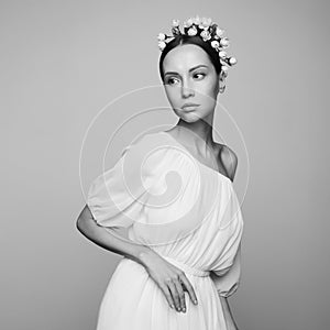 Woman in white greek dress with flowers on her head