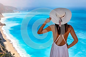 A woman with white hat looks at the blue sea of Egremni Beach at Lefkada island, Greece photo
