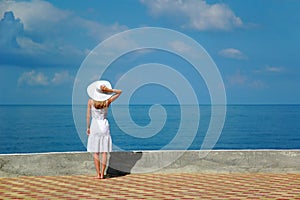 Woman in white hat looks at sea