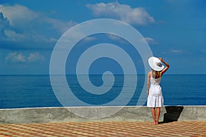 Woman in white hat looks at sea