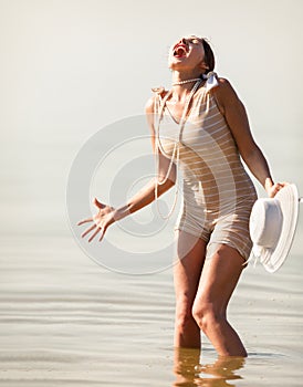 Woman in white hat posing against the sea