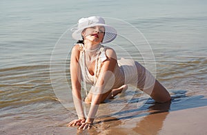 Woman in white hat posing against the sea