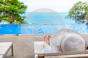 Woman with white hat relax at the pool beside the ocean