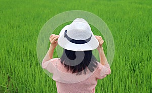 Woman in white hat relaxing in green paddy field