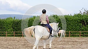 Woman on white horse doing horseback riding.