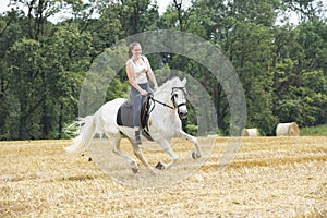Woman on white horseback on stubblefield photo