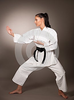 Woman in white kimono punch hard in the air - a karate martial