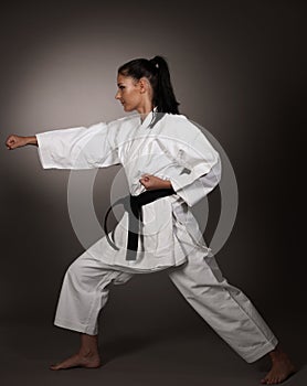 Woman in white kimono punch hard in the air - a karate martial art girl