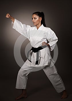 Woman in white kimono punch hard in the air - a karate martial art girl