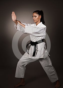 Woman in white kimono punch hard in the air - a karate martial art girl