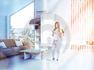 Woman in white living room interior, beige sofa