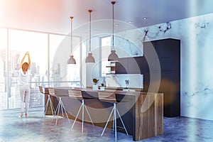 Woman in white marble kitchen corner with bar