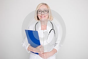 Woman in a white medical clothes and glasses standing isolated on a blue background.