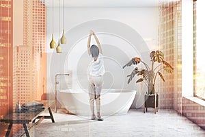 Woman in white and orange bathroom with white tub