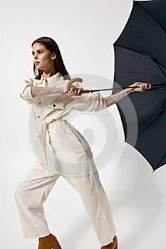 Woman in white overalls holding an umbrella from the wind basing isolated background