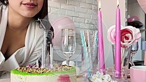 Woman in white party clothes preparing birthday table blowing candles