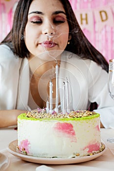 Woman in white party clothes preparing birthday table making wish