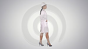 Woman in white robe putting hard hat on while walking on gradien