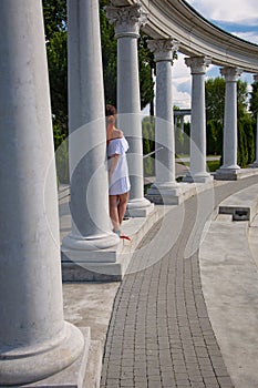 Woman in white romantic dress at Greek or Roman column with colonnade. Summer vacation. Travel destination. Summer fashion.