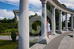 Woman in white romantic dress at Greek or Roman column with colonnade. Summer vacation. Travel destination. Summer fashion.