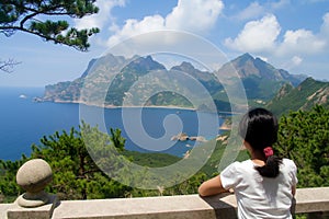 Woman in a white shirt admires view of coastal mountain range from overlook