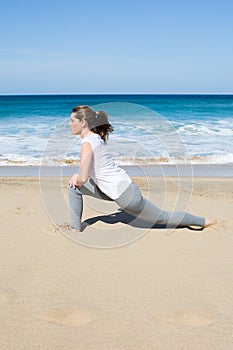 Woman in white shirt stretches on beach