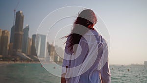 Woman in a white shirt walks along the beach of the Persian Gulf in Dubai