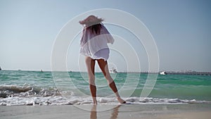 Woman in a white shirt walks along the beach of the Persian Gulf in Dubai