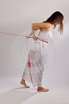 Woman white silk nightie lifting pulling red thread on white background