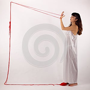 Woman white silk nightie making frame with red thread looking at her hand on white background