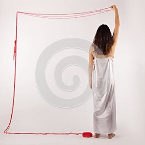 Woman white silk nightie making frame with red thread on white background