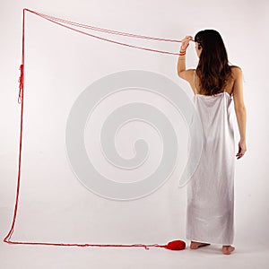 Woman white silk nightie making frame with red threadseen from her back on white background