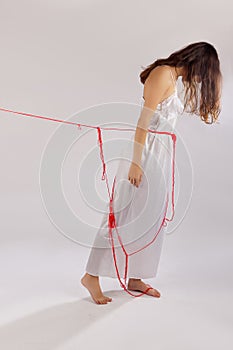 Woman white silk nightie pulling red thread on white background