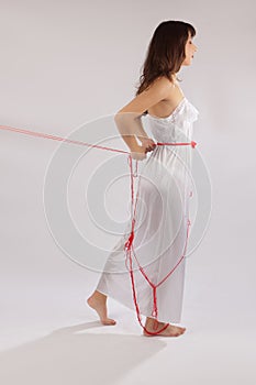 Woman white silk nightie pulling red thread on white background