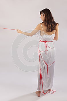 Woman white silk nightie pulling red thread on white background