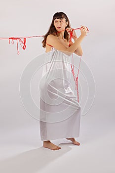 Woman white silk nightie pulling weg red thread on white background