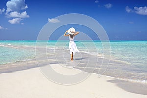 A woman in a white summer dress stands on a sandbar