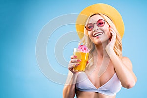 Woman in white swimsuit is drinking cocktail