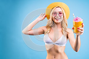 Woman in white swimsuit is drinking cocktail