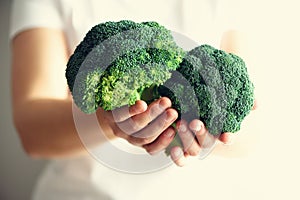 Woman in white T-shirt holding broccoli in hands. Copy space. Healthy clean detox eating concept. Vegetarian, vegan, raw