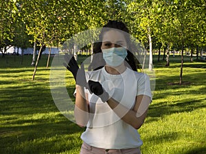 A woman in a white t-shirt and protective face mask is showing that you need to wear gloves in public places.