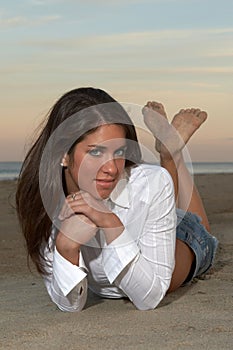 Woman in White Tailored Top Lying on Stomach with Ankles Crossed photo