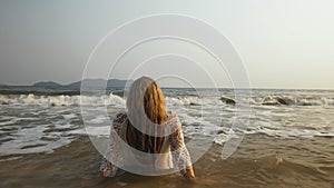 Woman in a White Tunic on the Beach, near the Sea. Blonde in Sun