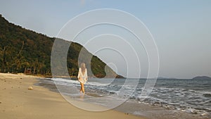 Woman in a white tunic on the beach, near the stormy sea. Blonde