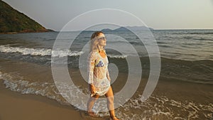 Woman in a white tunic on the beach, near the stormy sea. Blonde