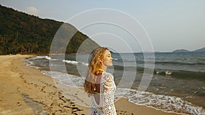 Woman in a white tunic on the beach, near the stormy sea. Blonde