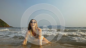 Woman in a white tunic on the beach, near the stormy sea. Blonde