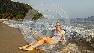 Woman in a white tunic on the beach, near the stormy sea. Blonde