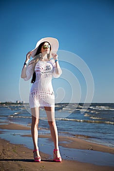 Woman in white tunic with white hat on the beach. Sea