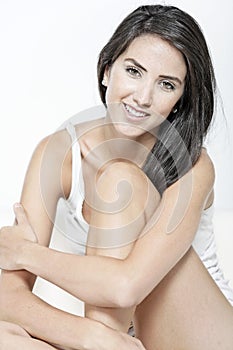 Woman in white vest top sitting on sofa